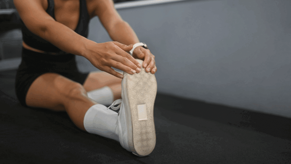 Young sporty woman sitting and stretching her legs after working out in the gym - The Importance of Stretching in Injury Prevention