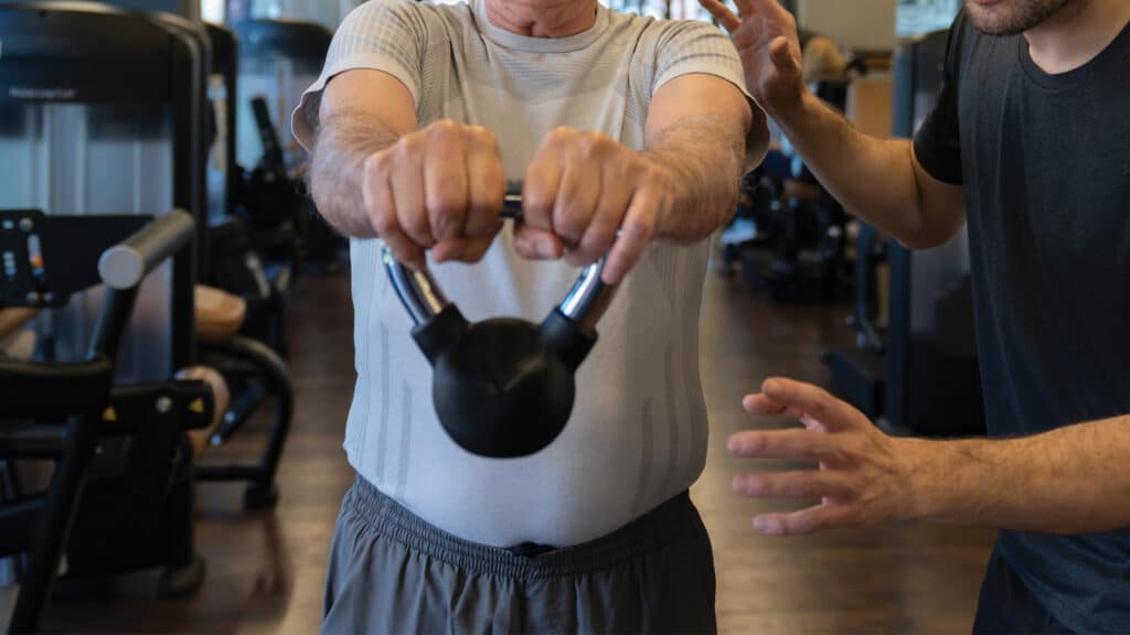 Older man performing kettle bell corrective exercise at Peake Movement, Baltimore, MD