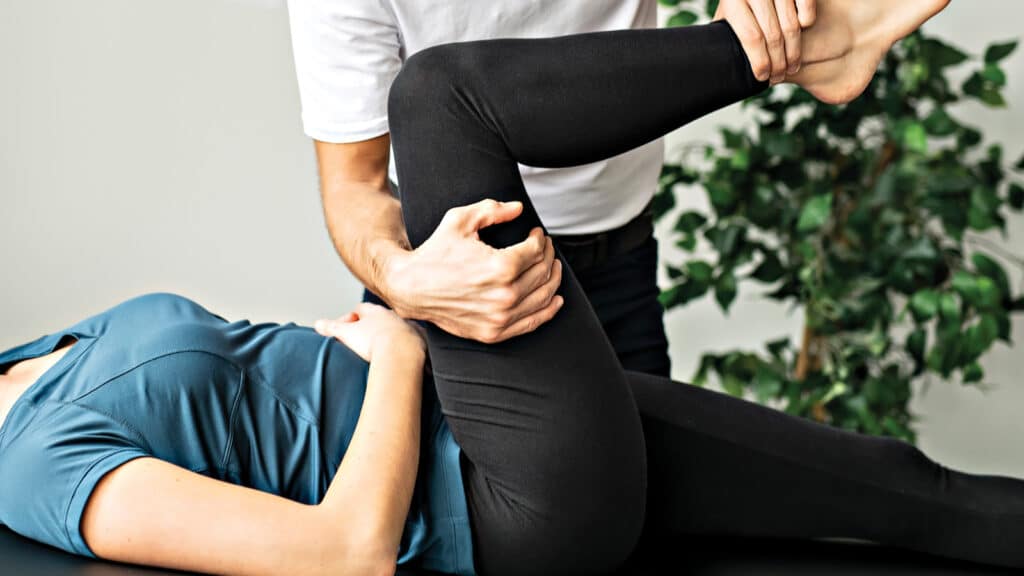 Physical therapist assisting a patient stretch her leg